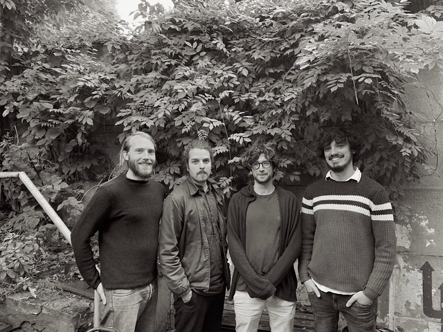 4 jeunes hommes devant un buisson