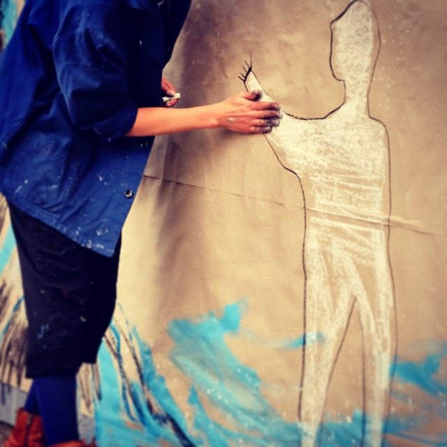 Cécile faisant un dessin à la craie sur un mur.