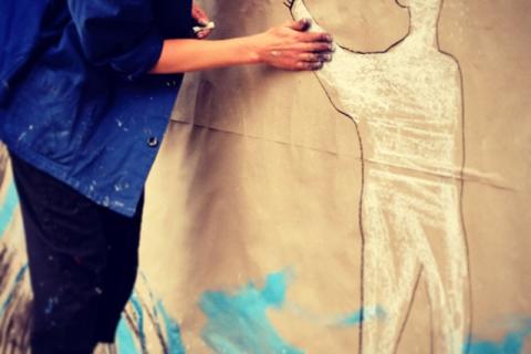 Cécile faisant un dessin à la craie sur un mur.
